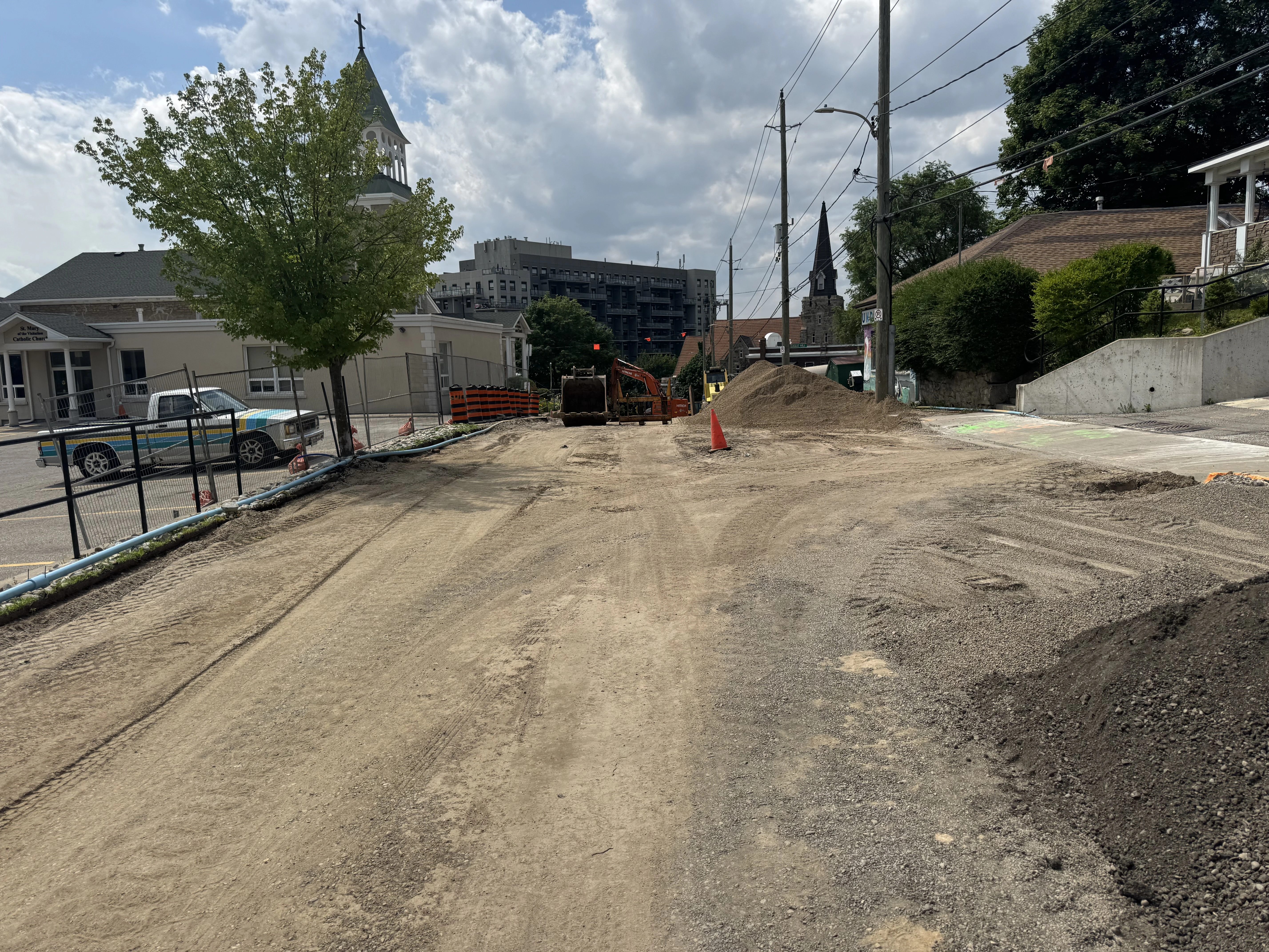 Cooper St (Construction) - Construction site with unpaved road, excavator, and gravel piles